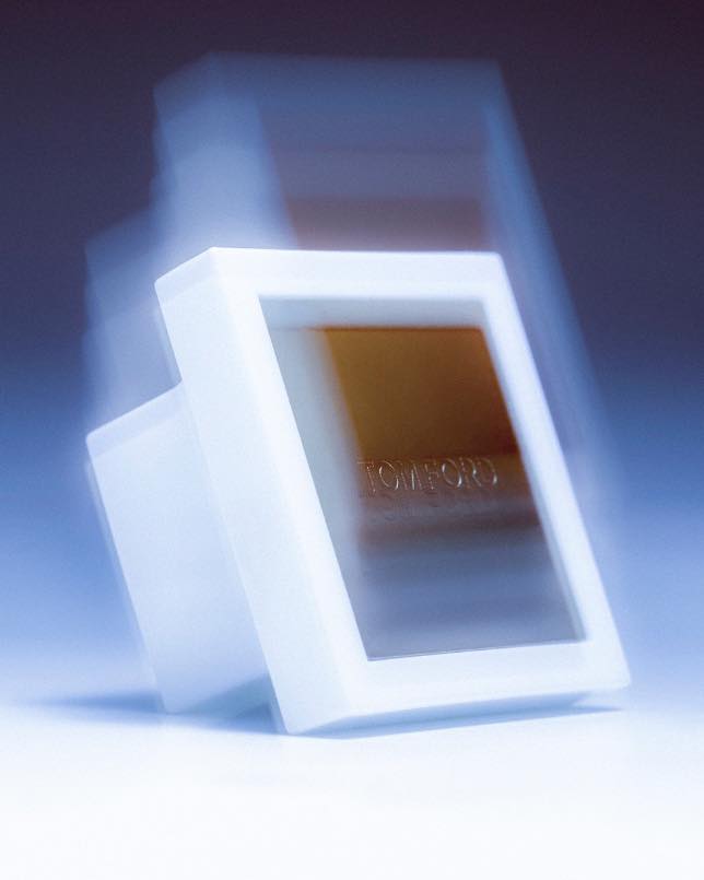Tom Ford bronzer with packaging in a white case, angled and blurred, set against a soft blue background.