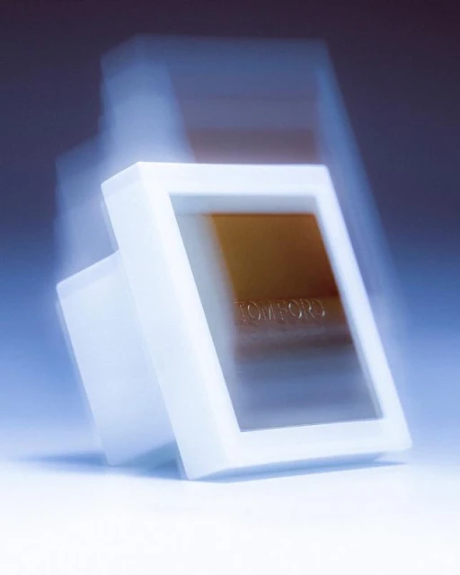 Tom Ford bronzer with packaging in a white case, angled and blurred, set against a soft blue background.