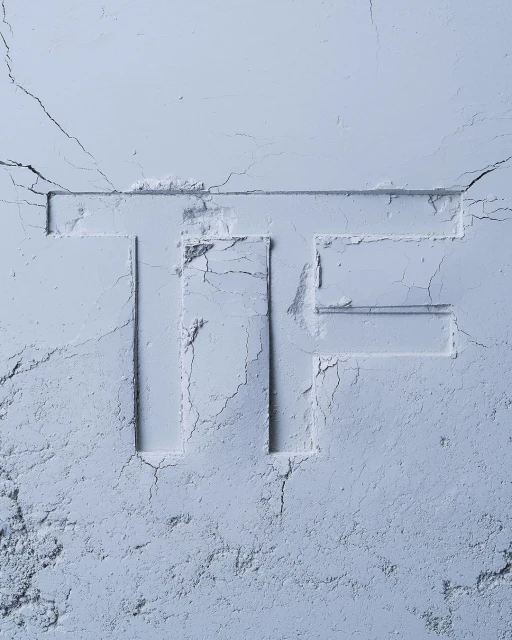 Monochromatic close-up of light blue cosmetic powder, with the letter 'TF' imprinted. Soft texture and subtle shadows create a gentle aesthetic.