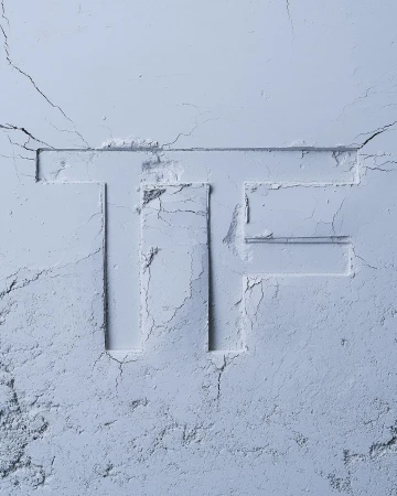 Monochromatic close-up of light blue cosmetic powder, with the letter 'TF' imprinted. Soft texture and subtle shadows create a gentle aesthetic.