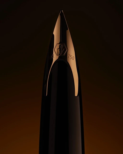 Close-up shot of a fountain pen nib with the number 750. The nib is partially gold and black. Brown gradient background.