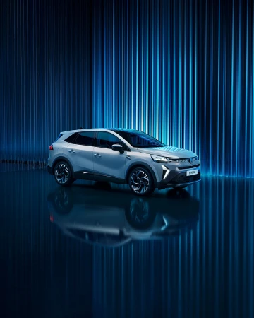 Sleek silver SUV parked indoors with dynamic blue lighting reflecting on a glossy surface, showcasing modern automotive design and technology.