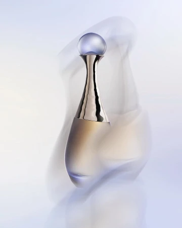 Amphora-shaped perfume bottle with a metallic neck and round purple cap wrapped in swirling translucent fabric in soft light.