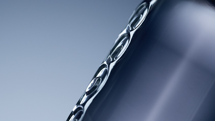 Close-up studio shot of a sleek, metallic container with curved edges, smooth surface, and cool, gradated blue background.