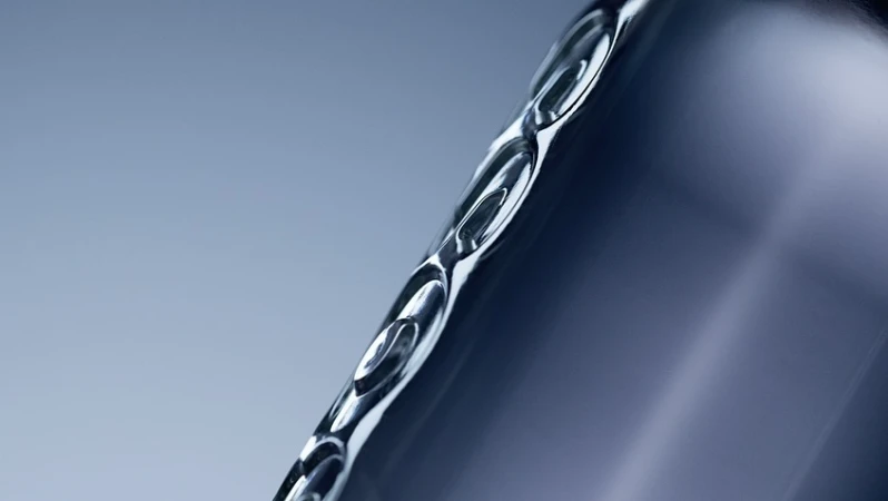Close-up studio shot of a sleek, metallic container with curved edges, smooth surface, and cool, gradated blue background.