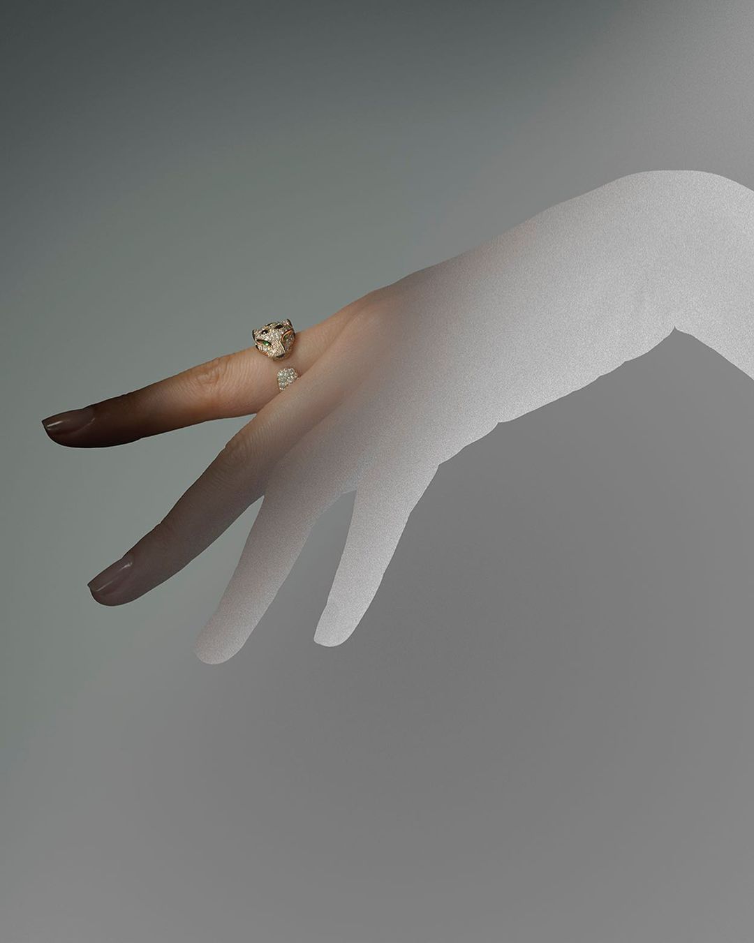 Hand with an animal-shaped gold ring on the index finger against a grey background, showcasing fashion and jewelry.