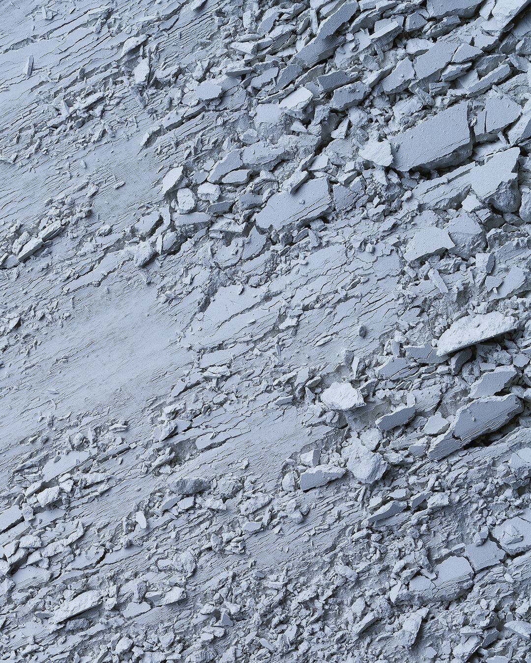 Abstract close-up of fragmented material shows a textured surface with cracks and scattered pieces, offering a monochromatic look.