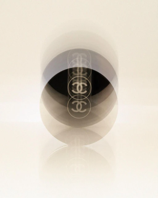 High-key studio shot of a Chanel No. 5 perfume bottle with multiple exposures against a graduated white background. Fashion, Beauty.