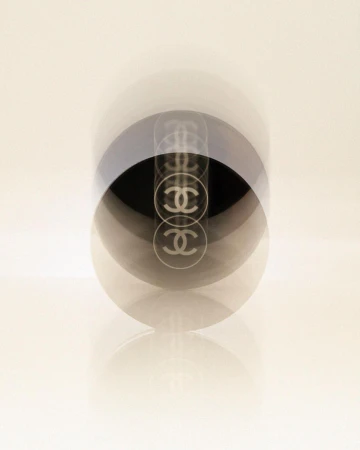 High-key studio shot of a Chanel No. 5 perfume bottle with multiple exposures against a graduated white background. Fashion, Beauty.