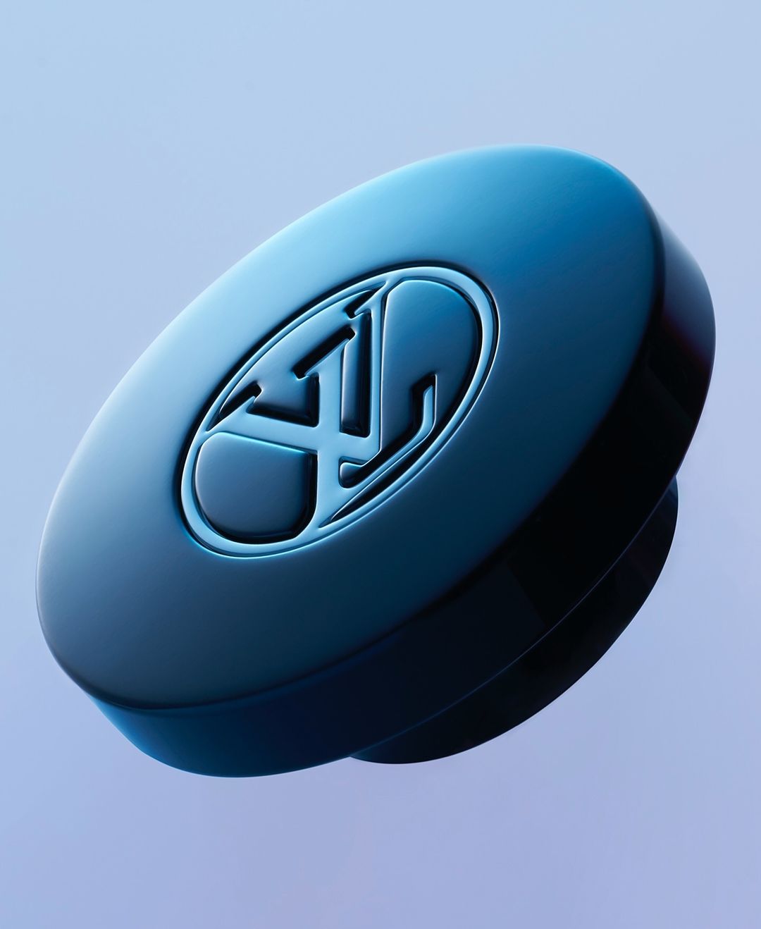 Close-up of a round, blue-toned device or component featuring a debossed logo, set against a soft, gradient blue background.