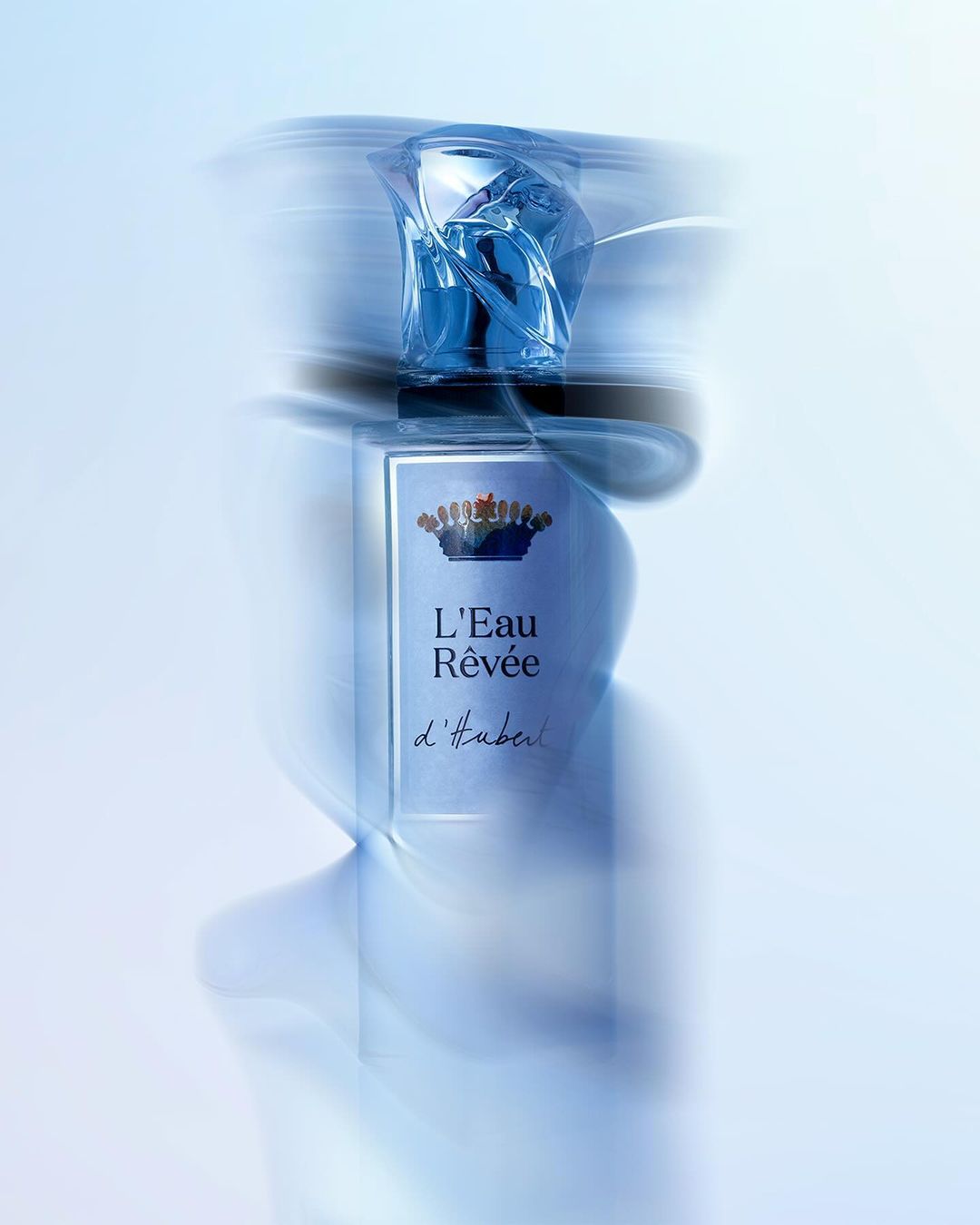Perfume bottle with blue liquid and ornate cap captured with long exposure motion blur against a light background