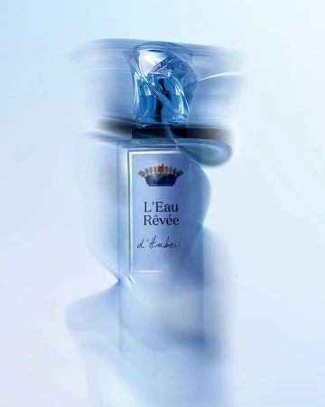 Perfume bottle with blue liquid and ornate cap captured with long exposure motion blur against a light background