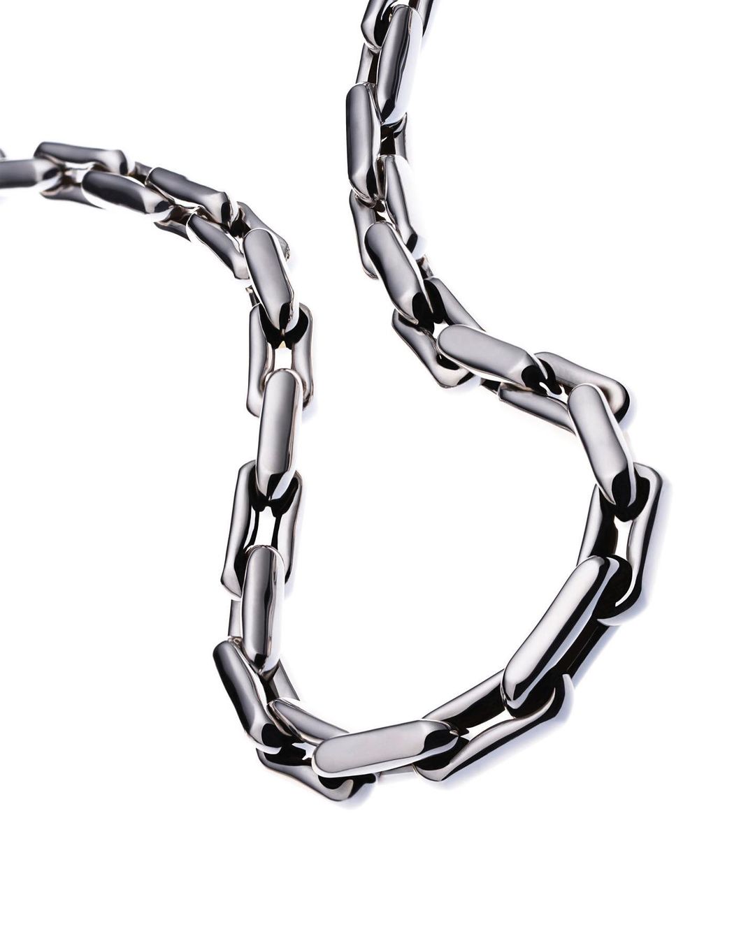 Metal chain necklace on a white background. Shiny metal links form a smooth loop. Close-up view emphasizes material texture and design.