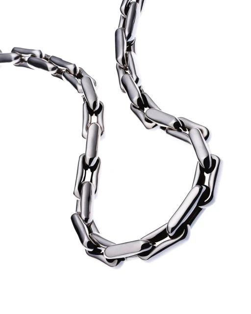 Metal chain necklace on a white background. Shiny metal links form a smooth loop. Close-up view emphasizes material texture and design.