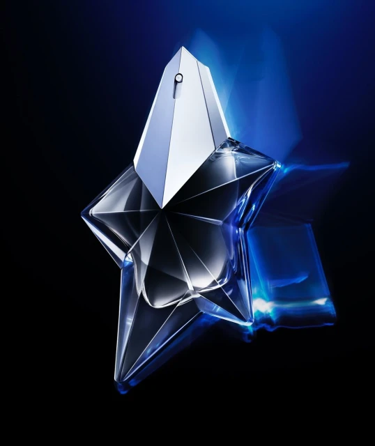 Star-shaped perfume bottle on a black surface with blue light reflecting. Commercial shot with cool tones for a luxury fragrance ad.