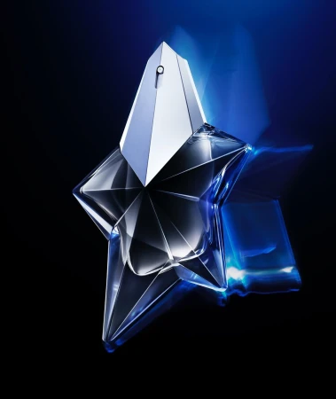 Star-shaped perfume bottle on a black surface with blue light reflecting. Commercial shot with cool tones for a luxury fragrance ad.