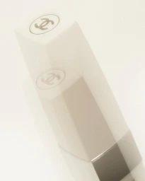 Close-up macro shot of a white Chanel lipstick tube against a clean light background by Akatre.