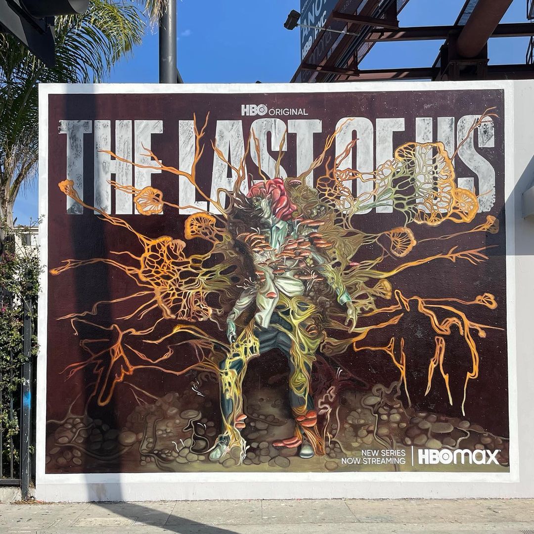 Outdoor billboard advertisement for HBO's 'The Last of Us' featuring a central figure entwined with fungal elements against a dark background.