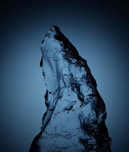 Translucent blue ice or glass chunk against a gradient blue backdrop, presenting an abstract and cold-toned visual texture.