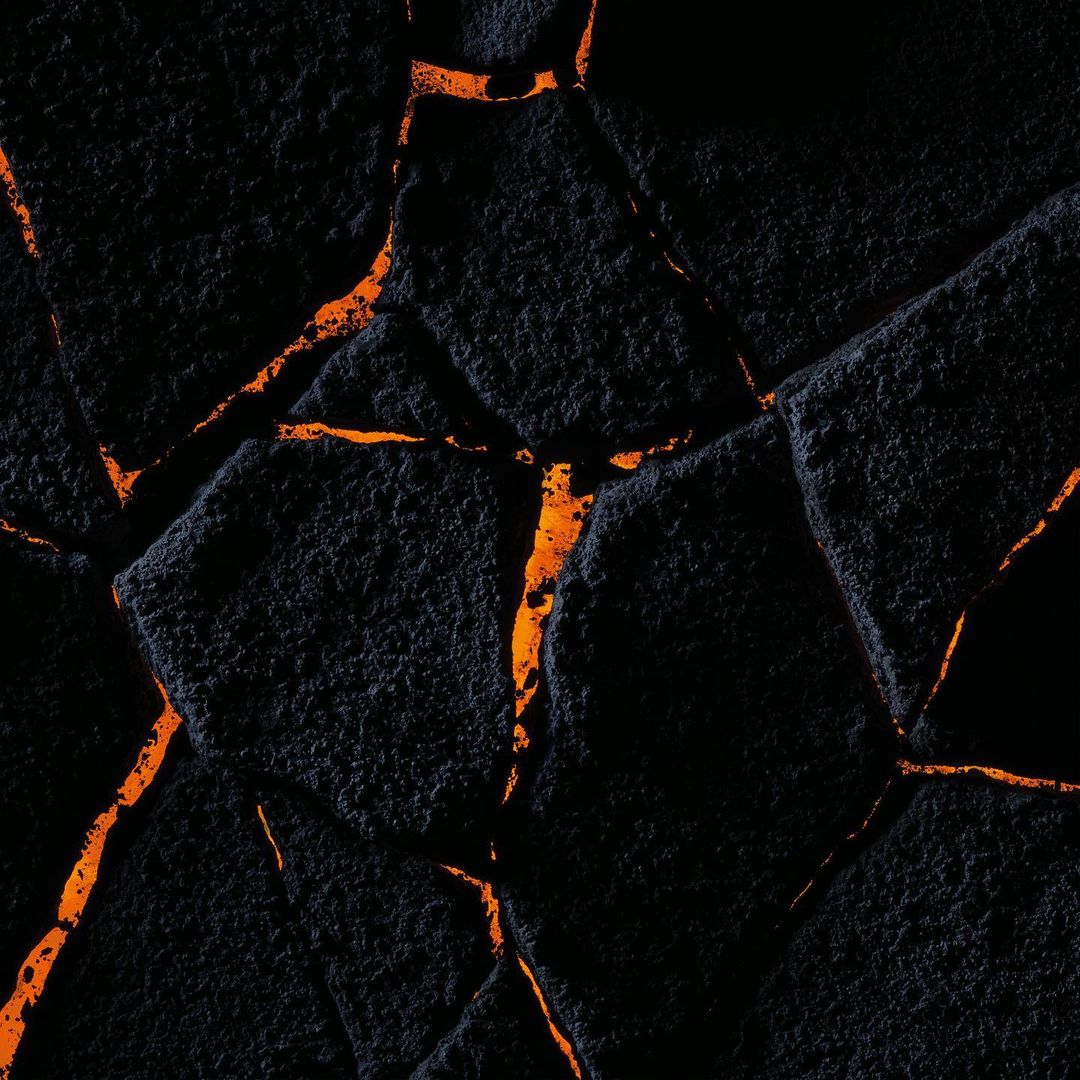 Abstract image of black cracked surface with bright orange glowing fissures, creating a stark contrast between darkness and light.