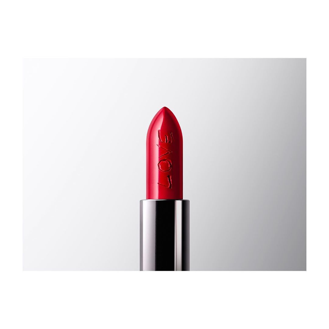 Close-up of red lipstick tube with 'LOVE' engraved, against a white backdrop, ideal for beauty product advertising and cosmetic promotions.