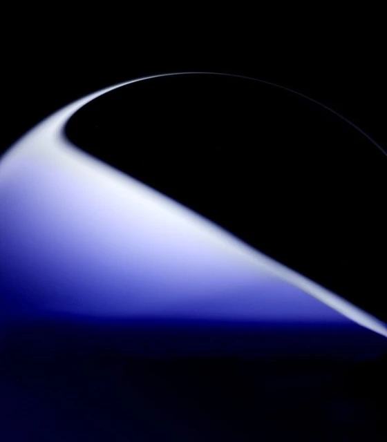 Abstract image with a curved white shape transitioning to blue against a black background, creating a sense of depth and contrast.