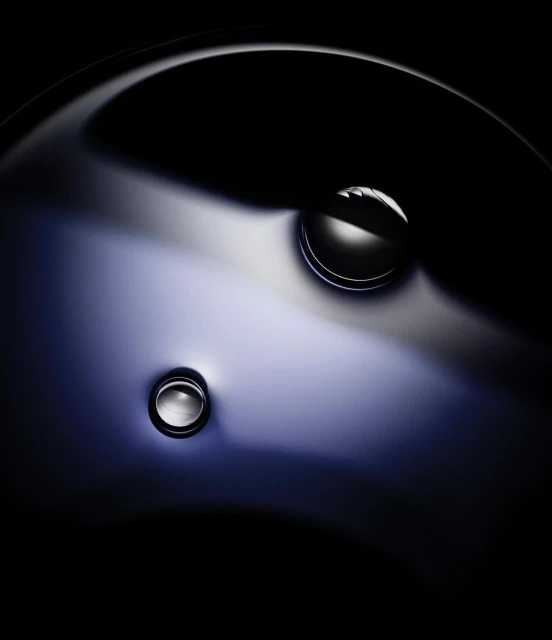 Abstract close-up of a polished, possibly metal, surface with two shiny, spherical elements with a dark background.