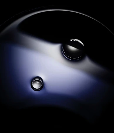 Abstract close-up of a polished, possibly metal, surface with two shiny, spherical elements with a dark background.