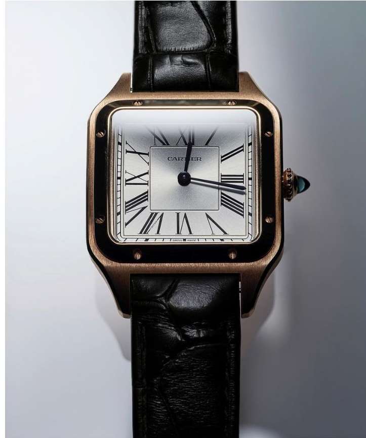 Close-up of a gold Cartier wristwatch with a black leather strap and a square silver face, displaying Roman numerals and black hands.