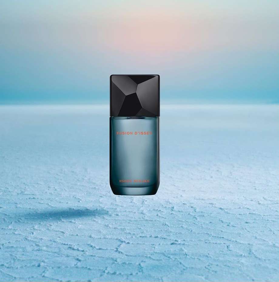Still life studio shot of Issey Miyake L'Eau d'Issey Eau de Toilette Intense perfume bottle on a textured light blue surface with soft lighting.