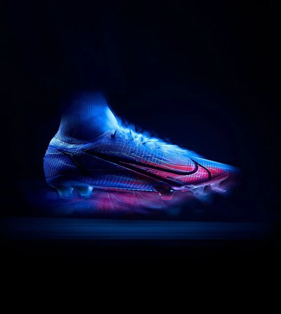 High-cut blue Nike Mercurial soccer cleat with a red swoosh logo against a dark background in a studio product shot. 
