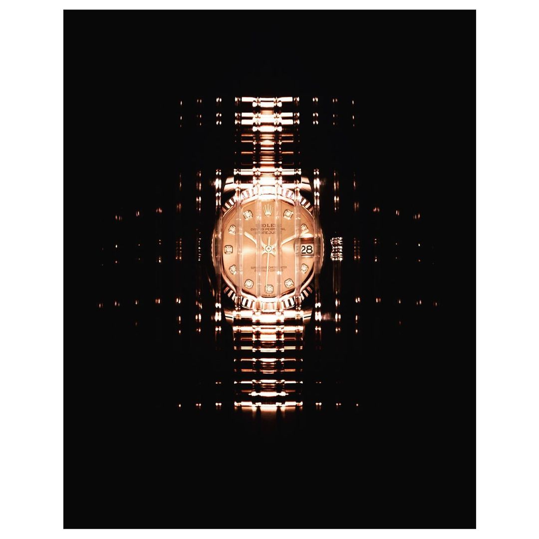 Elegant gold Rolex wristwatch on a black background with mirrored light reflections, emphasizing luxury and high-end craftsmanship.