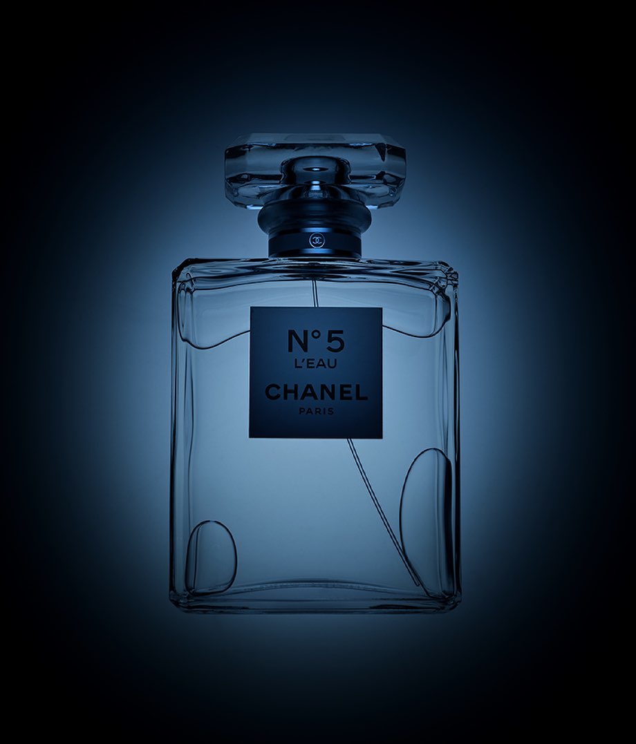 Elegant studio shot showcasing a Chanel N°5 L'Eau perfume bottle, emphasizing its design and brand with a cool blue color palette.
