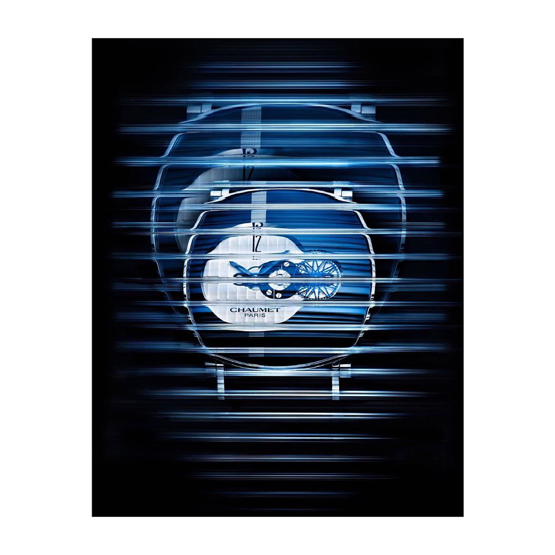 Luxury wristwatch with a blue face and silver band, featured in a studio product shot with abstract, blurred, light streaks.