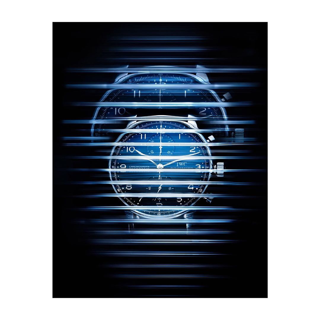 Close-up product photography of a silver wristwatch featuring a blue face, positioned between blurred horizontal bars against a dark background.