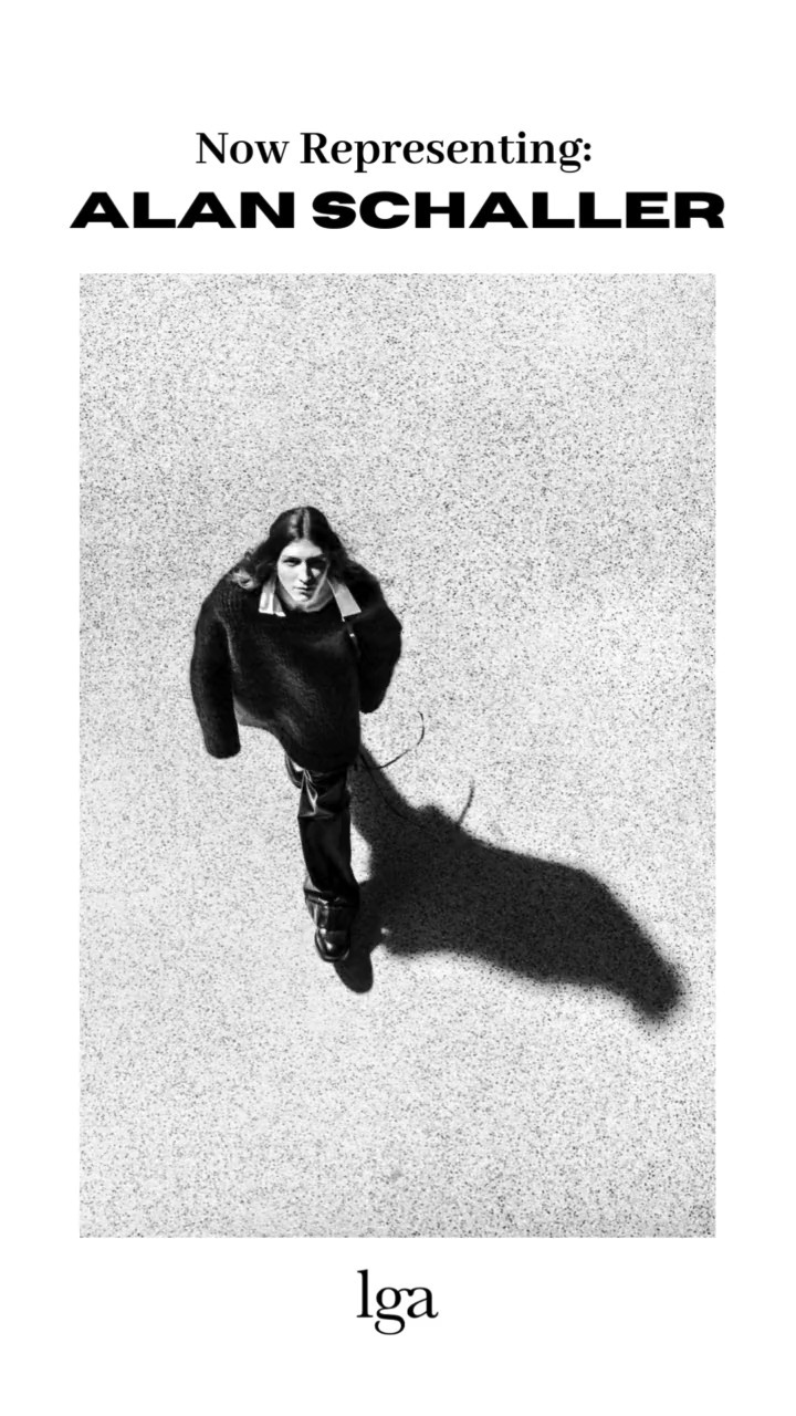 Full-length shot from above of a person with long hair in dark clothing, casting a long shadow on a speckled surface, with text above and below.