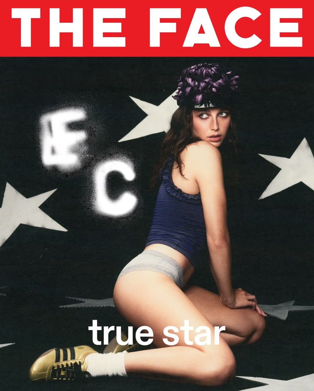 Magazine cover featuring a female model kneeling in a photo studio with black and white star background and a red banner at the top.
