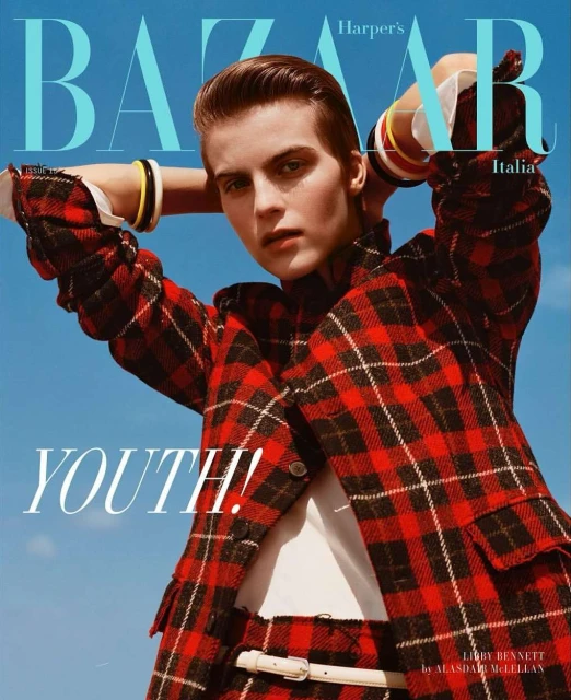 Bazaar Italia magazine cover featuring a woman in a red plaid suit and yellow bracelets against a light blue sky backdrop.