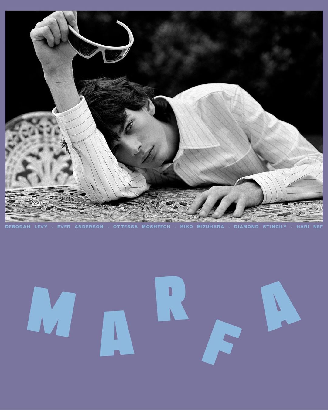 Black and white fashion shot of a young male model with sunglasses on a table, posing outdoors in a patterned shirt, with text overlay.