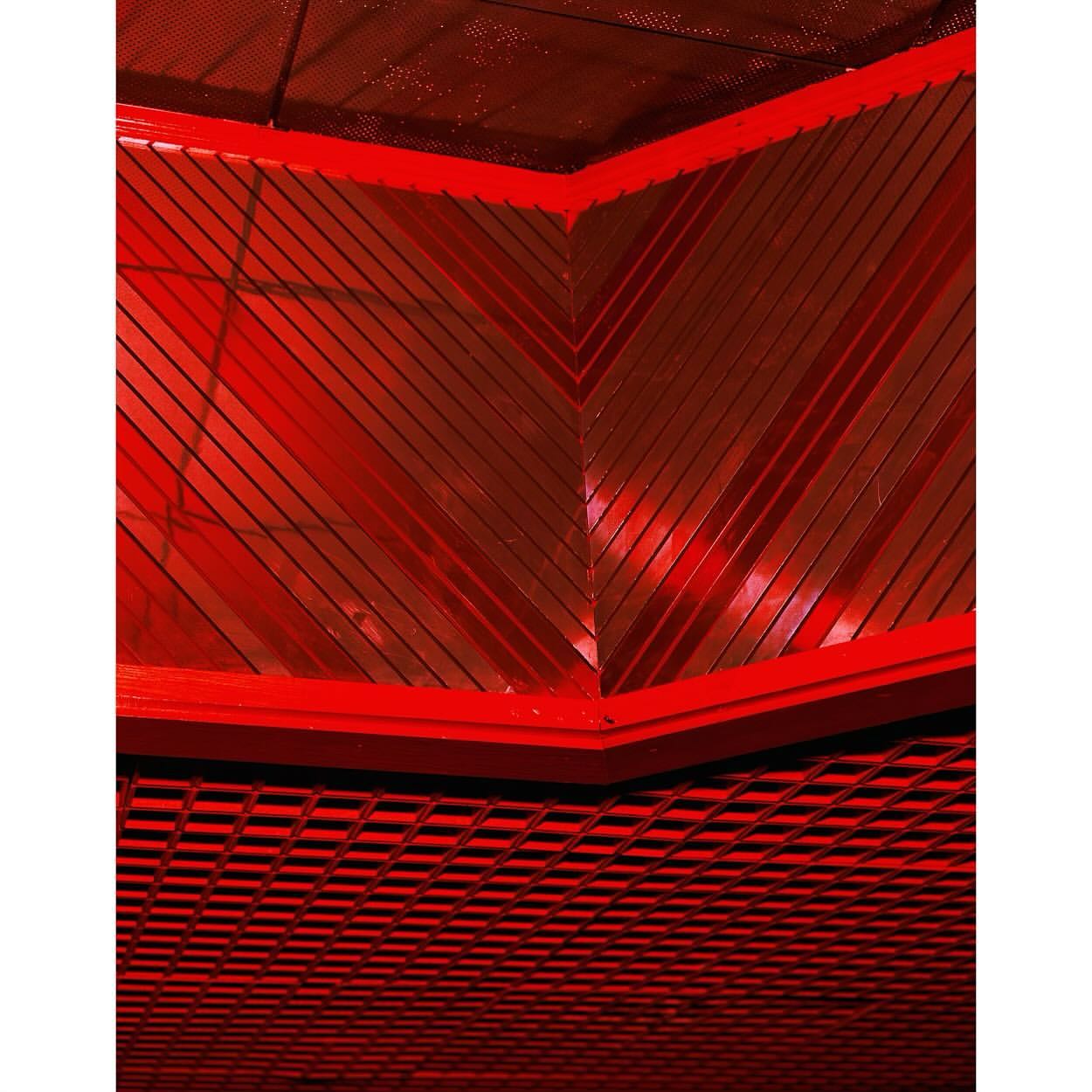 Abstract view of a red-toned architectural structure with geometric patterns and lines, showcasing a modern and visually striking design.