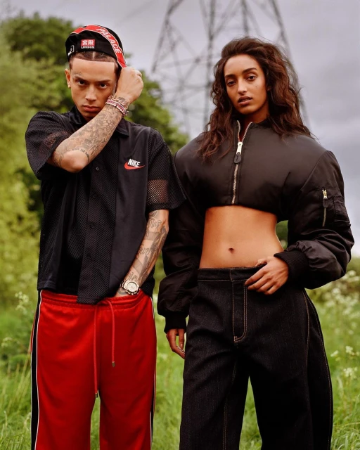 Two fashion models pose outdoors in athletic-inspired streetwear with an overhead powerline backdrop on an overcast day.