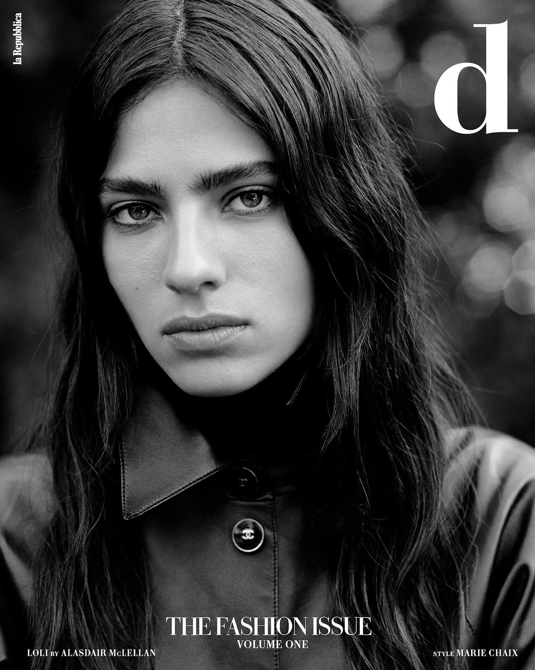 Black and white fashion magazine cover featuring a woman with long dark hair wearing a collared shirt, soft lighting, and bokeh background.