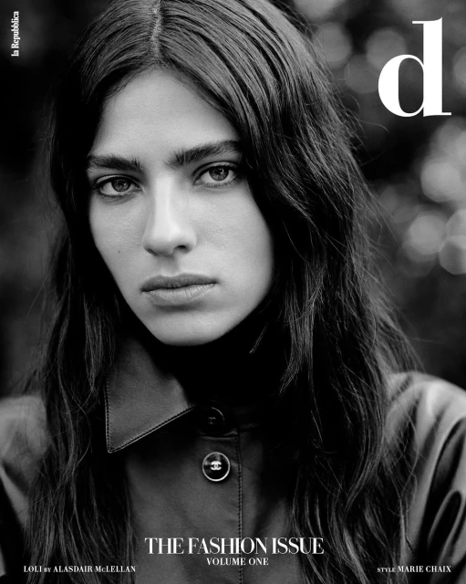Black and white fashion magazine cover featuring a woman with long dark hair wearing a collared shirt, soft lighting, and bokeh background.