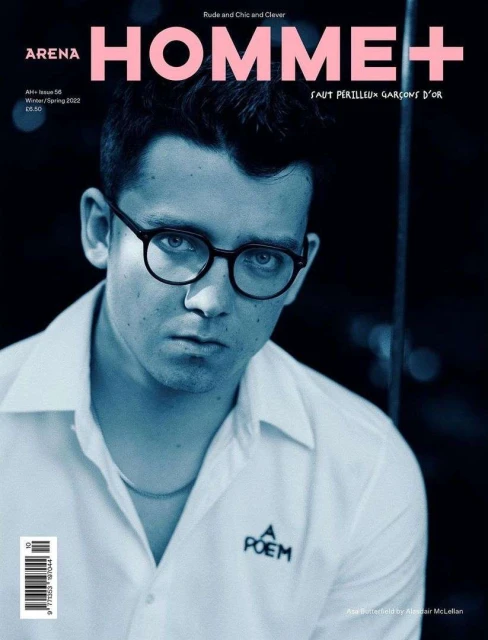 Magazine cover featuring a portrait of a young man with glasses wearing a white collared shirt against a blurred dark background.