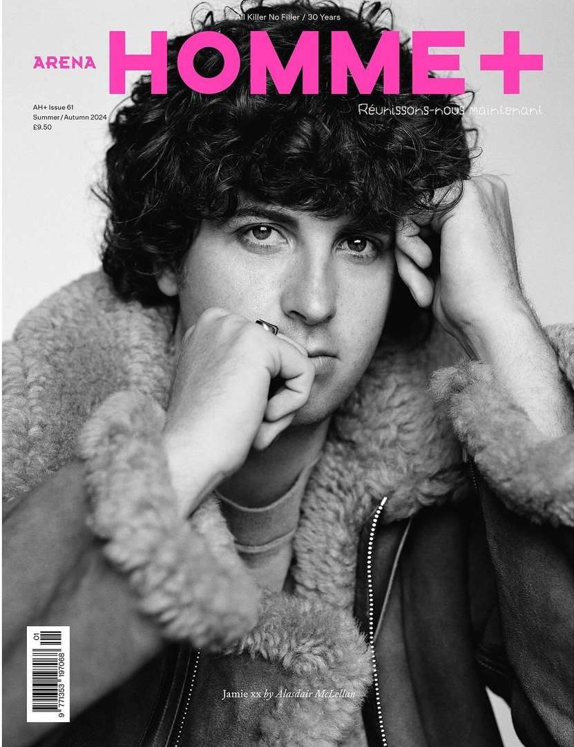 Black-and-white magazine cover featuring a young man with curly hair, wearing a fur-lined jacket, against a pale backdrop.