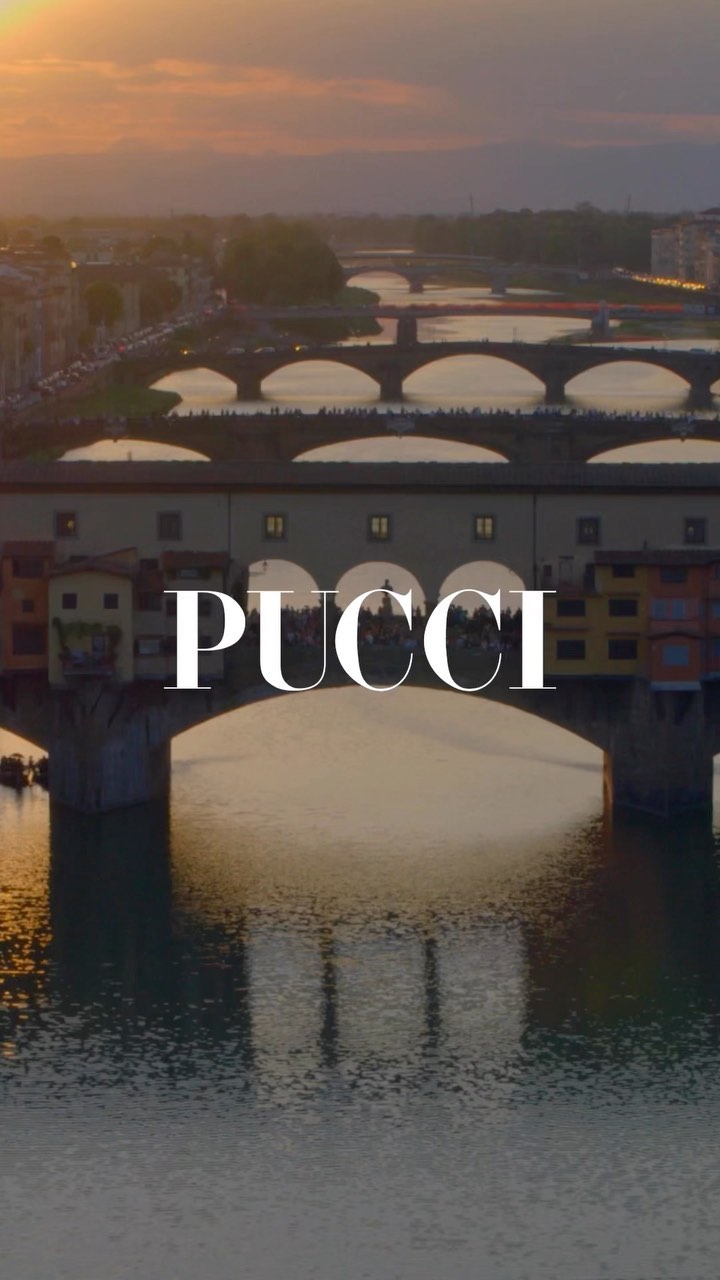 Scenic Ponte Vecchio bridge view in Florence, Italy, featuring the Arno River and distant buildings under a warm, golden sunset light.