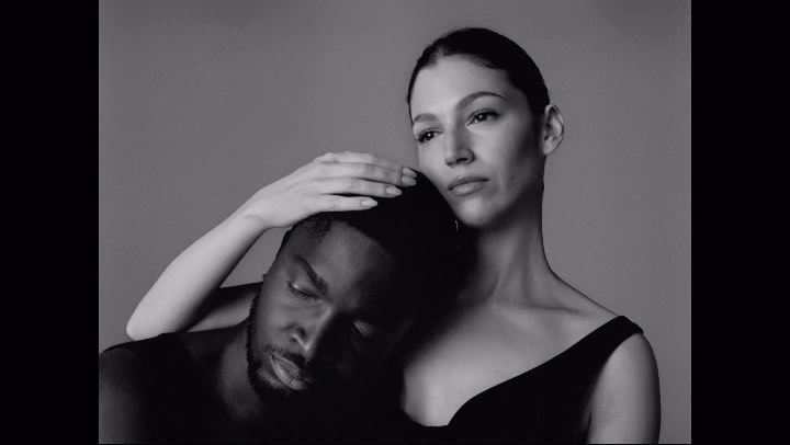 Monochromatic portrait of an African-American man with his head leaning against a Caucasian woman, studio setting, minimalist style.