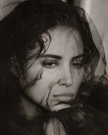 Close up portrait of a woman wearing a sheer black veil draped over her head, photographed by Albert Watson.