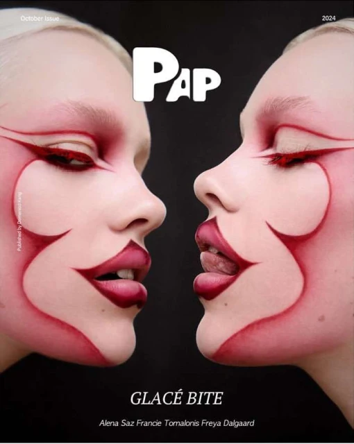 Closeup of two women with pale skin and artistic red eye and face makeup, with red lip makeup in a fashion editorial style.