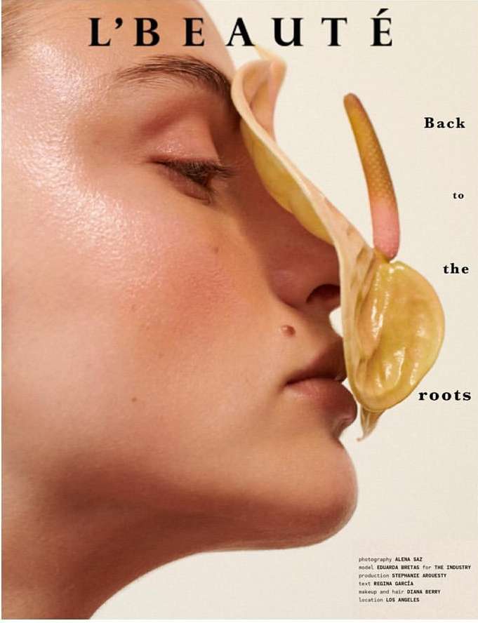 Close-up studio shot of a fair-skinned woman's face in profile with a large calla lily covering her eye and cheek in a beauty magazine ad.